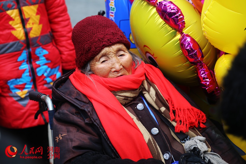 郑州90后创业青年为90岁气球奶奶系爱心围脖