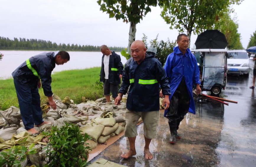 市国资委驻中牟县官渡镇吴庄村工作队动员群众搬运沙袋巩固河堤。