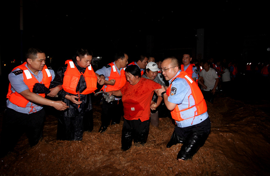 7月22日晚，河南省南阳市淅川县公安民警在洪水中搭成人墙保护受困群众脱离危险区域。周勇摄 