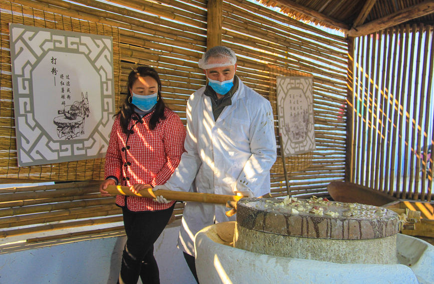 12月28日，河南省社旗县朱集镇殷河村，当地游客在生产作坊体验磨粉。高嵩摄