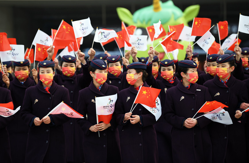 乘务员们挥舞国旗和冬奥会旗帜，为北京冬奥会喝彩。万彩林摄