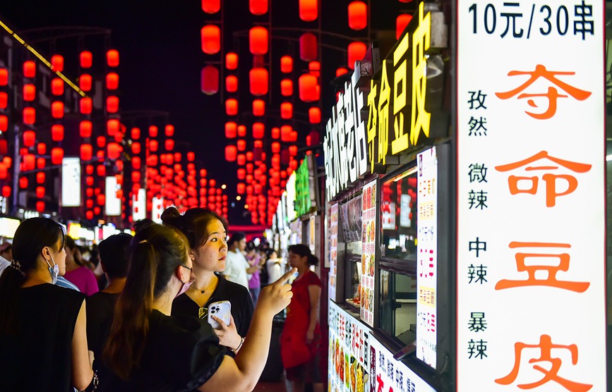 游客在洛阳古城历史文化街区“十字街”品尝小吃。黄政伟摄