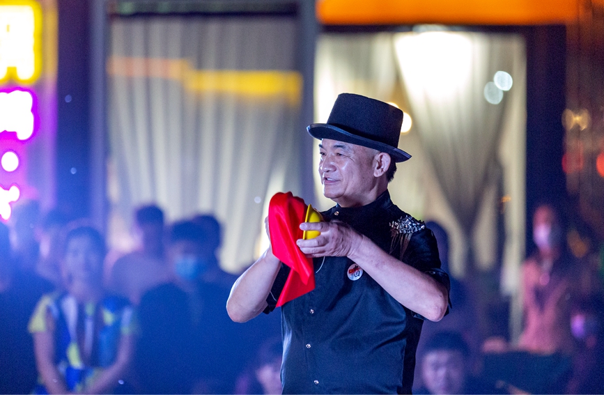 夜幕降临，魔术师在河南省安阳市安阳县西裴小镇的舞台上表演空中取水。王建安摄