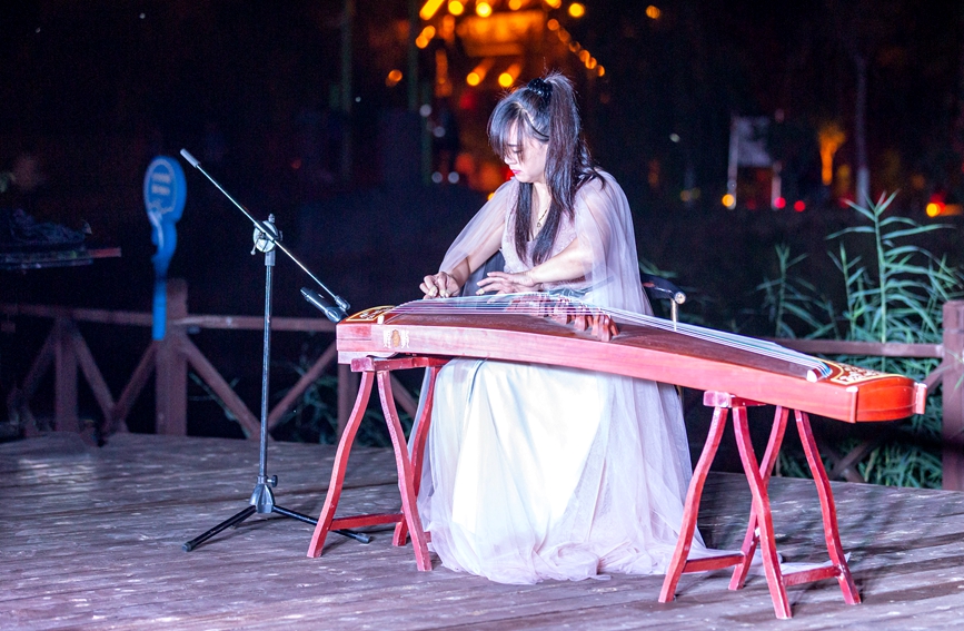 夜幕降臨，古箏演奏者在河南省安陽市安陽縣西裴小鎮的舞台上演奏傳統音樂《定風波》。王建安攝