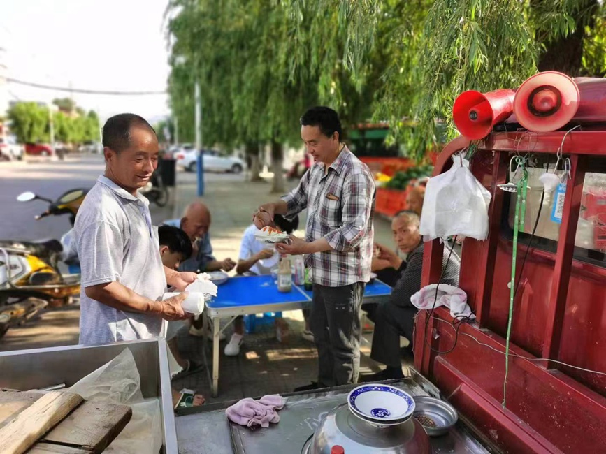 居民在刘庆海（左一）的摊子上吃热豆腐。