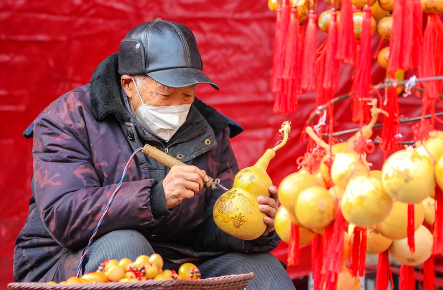 河南省南阳一处迎春活动广场，一位民间艺人在烙画，其烙画葫芦受到市民青睐。高嵩摄