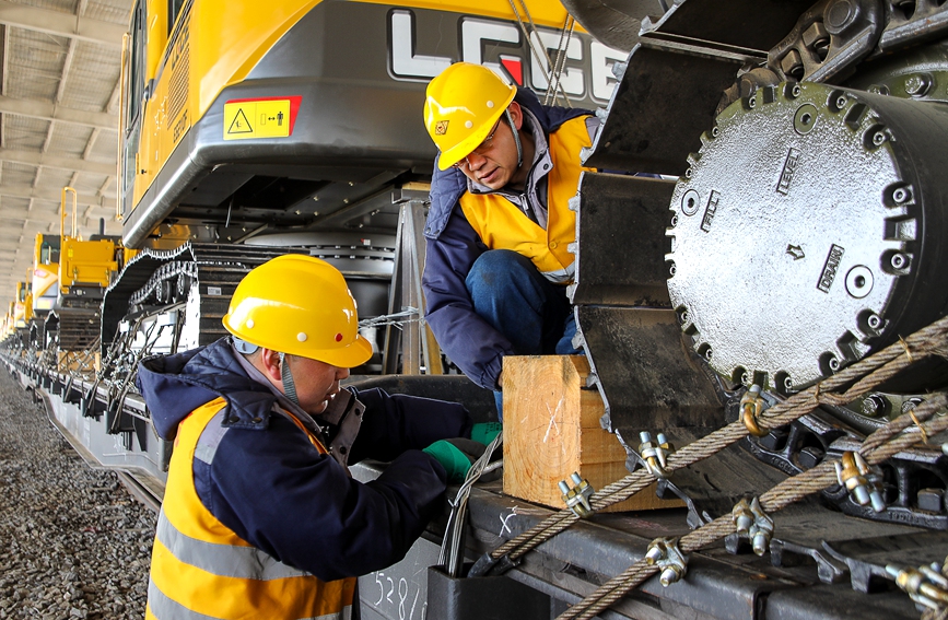 3月19日，中欧班列(中豫号·安阳)首发前夕，物流园区工作人员对列车上的挖掘机装载加固。麻翛然摄 