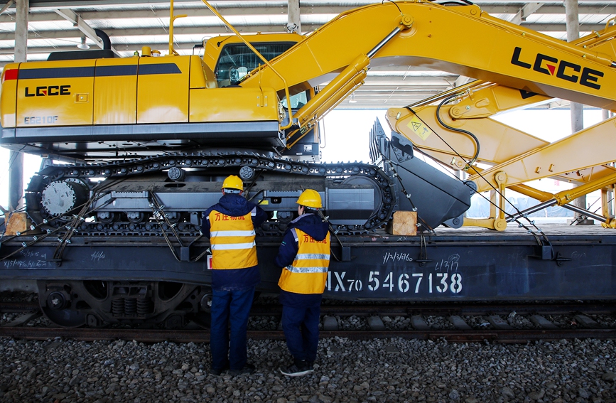 中欧班列(中豫号·安阳)首发前夕，工作人员对列车上装载的挖掘机固定情况做最后检查。麻翛然摄