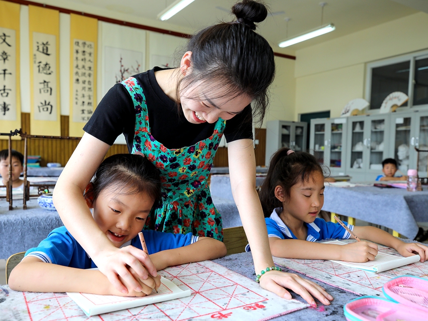 7月13日，安阳市高新区银杏南校书法暑期延时服务课，老师正在指导学生练字。麻翛然摄