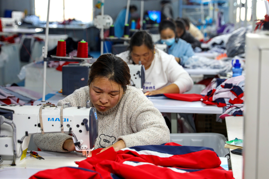 工人们在濮阳市清丰县六塔乡浩善实业有限公司生产车间里，缝制、修剪服装。清丰县委宣传部供图
