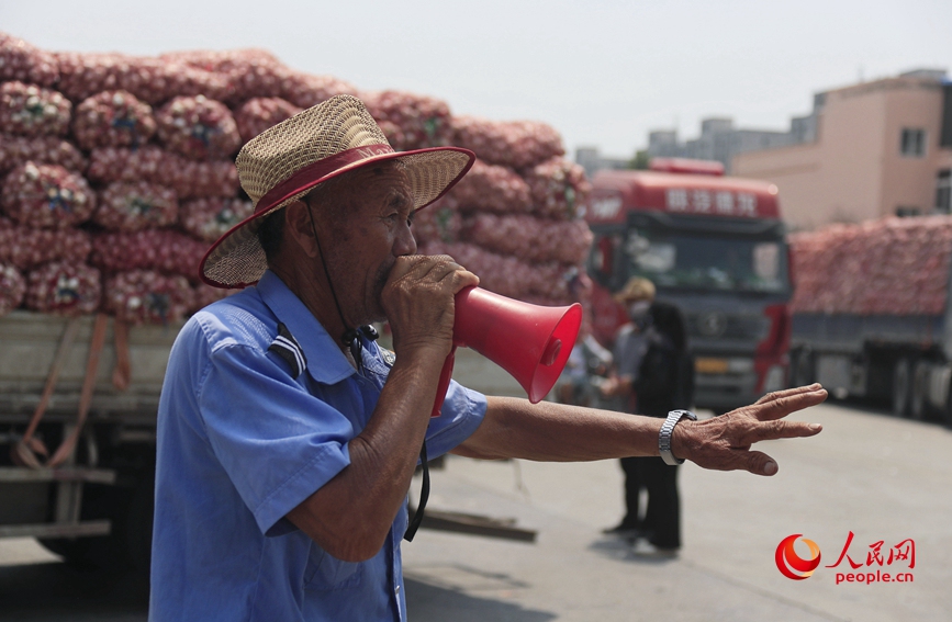 河南杞县大蒜交易市场里，工作人员在指挥交通。人民网 霍亚平摄