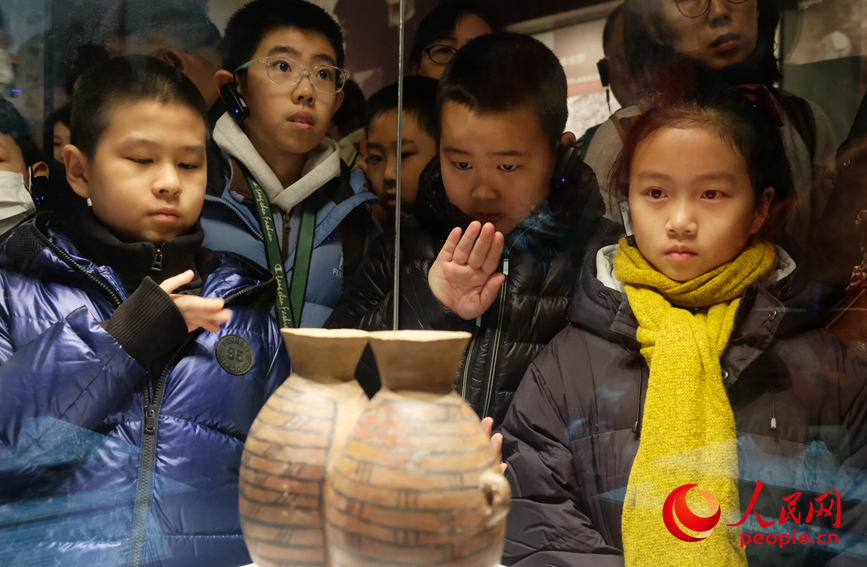 孩子们围在文物展柜前，认真听讲解。人民网 常力元摄
