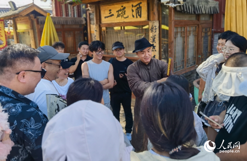 万岁山武侠城景区，演员与游客成语接龙，互动热烈。人民网记者 尚明桢摄