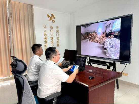 海关关员与企业人员通过手机远程连线对企业出口竹木草制品进行检查。郑州海关供图