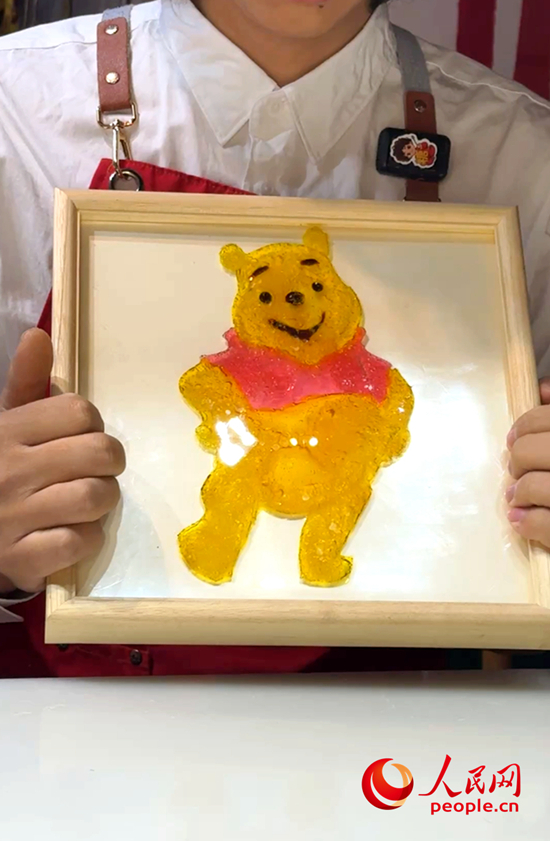 王岐洋向记者展示将糖画封入滴胶,制成的可悬挂墙面的艺术品。人民网记者 侯琳琳摄.jpg