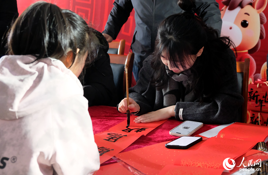 共青团开封市委组织青年书法志愿者为旅客现场挥毫送春联。人民网记者 常力元摄