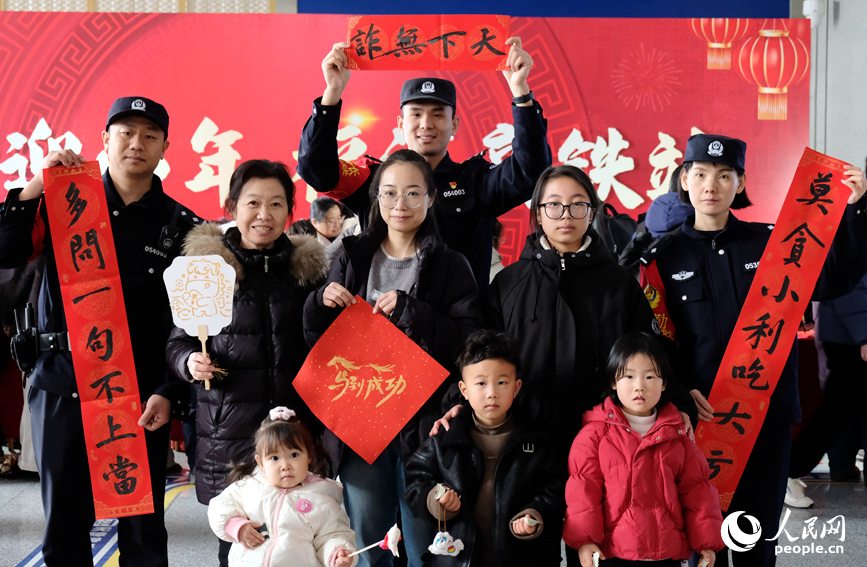 民警将反诈知识写进春联，与现场旅客合影打卡。人民网记者 常力元摄