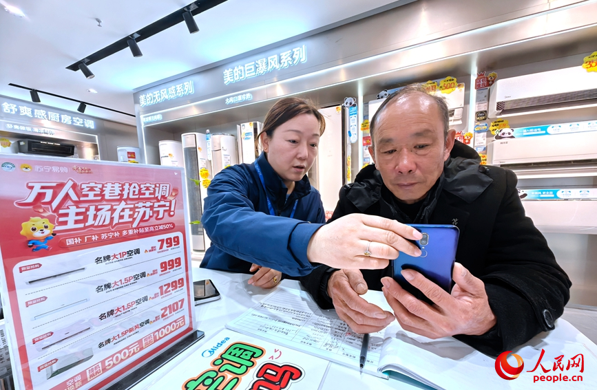 郑州一家电卖场内，销售人员指导顾客领取补贴。人民网记者 宋芳鑫摄