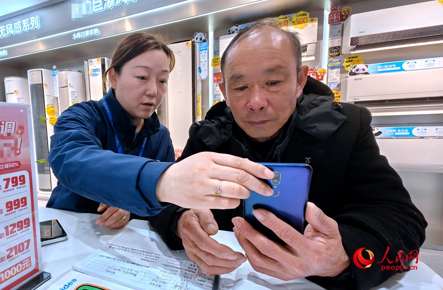 销售顾问杨丽在为徐先生介绍补贴政策。人民网记者宋芳鑫摄