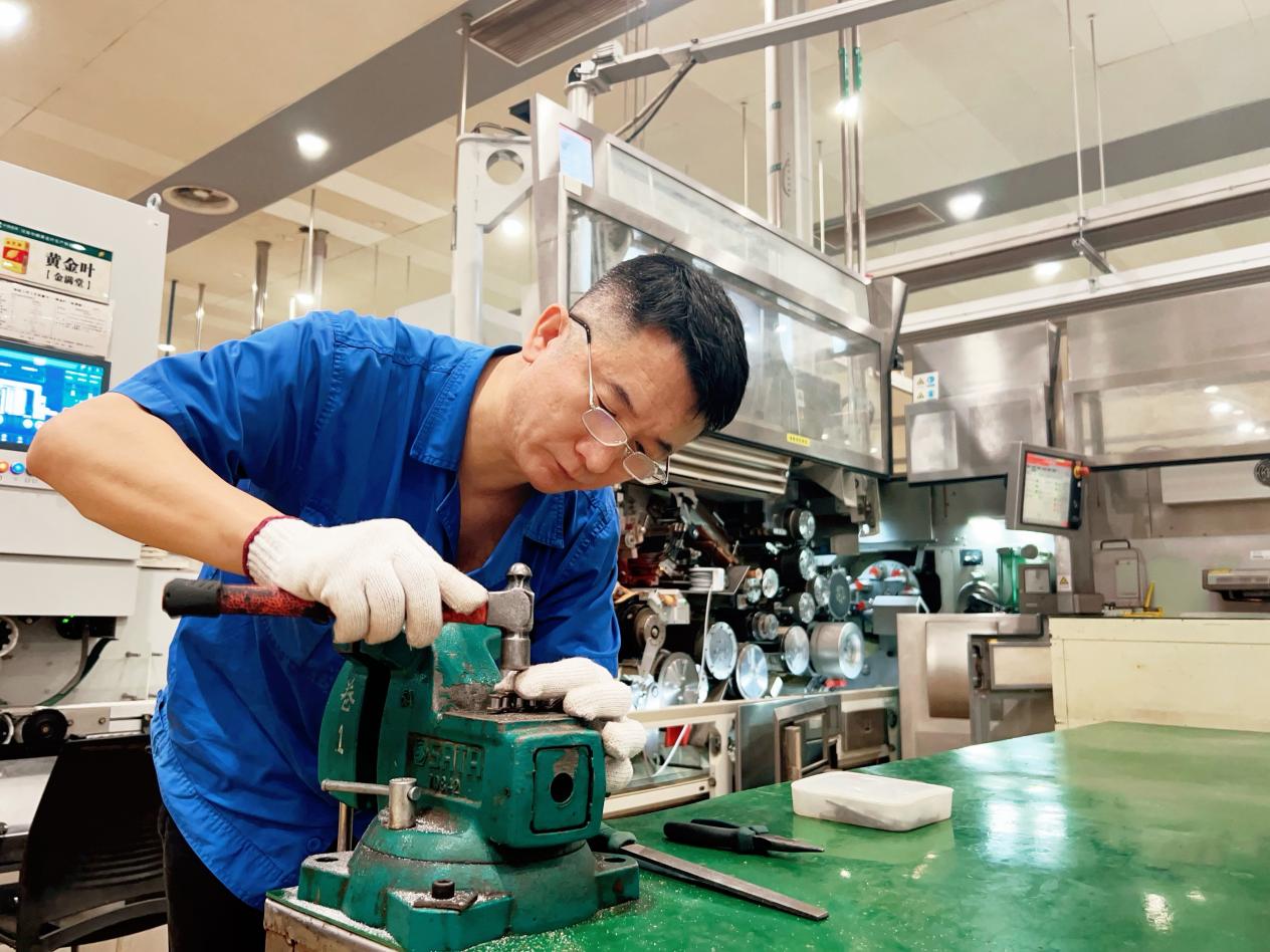 黄金叶生产制造中心卷包车间维修工正在调整设备零部件。河南中烟工业有限责任公司黄金叶生产制造中心供图