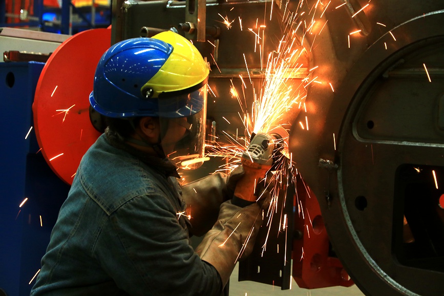 工人們正在用砂輪機打磨零部件上毛刺。王建棟攝