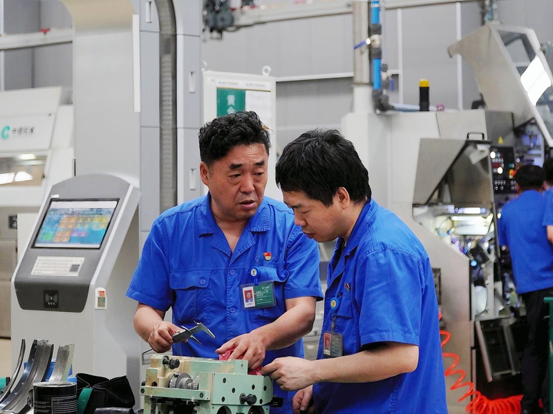 洛陽卷煙廠卷包車間電工喬晉偉與維修工討論設備拆解問題。鄧中元攝