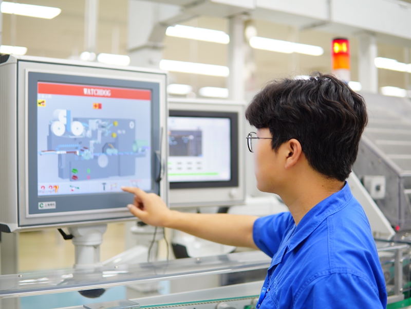 洛陽卷煙廠卷包車間青年操作工在設備屏幕上調整參數。鄧中元攝