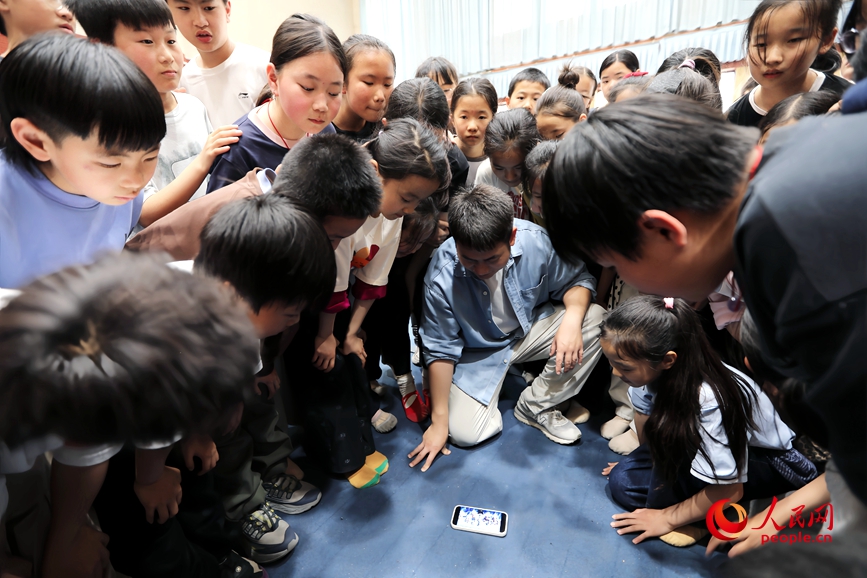 马超群和孩子们观看排练视频。人民网记者 霍亚平摄