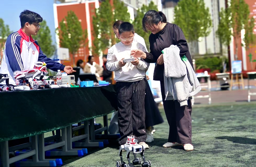 学生操控机器狗进行展示，吸引家长与同学驻足体验。张新军摄