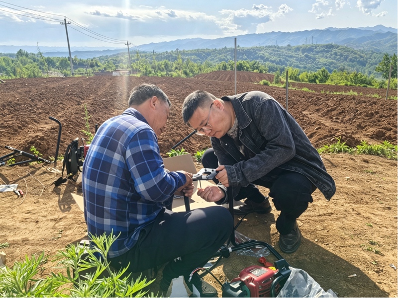 德亭煙站站長賈植顯助煙農組裝移栽打穴機。石岩攝