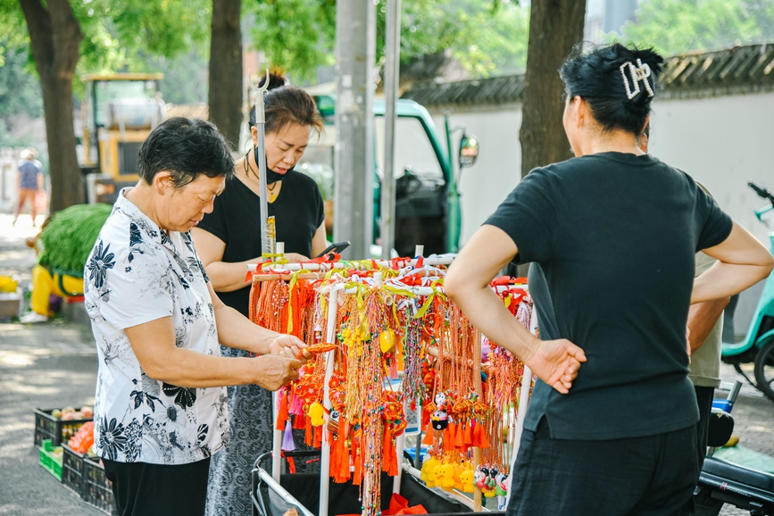 洛阳市老城区街头，市民挑选端午传统饰品，感受民俗氛围。王玺摄