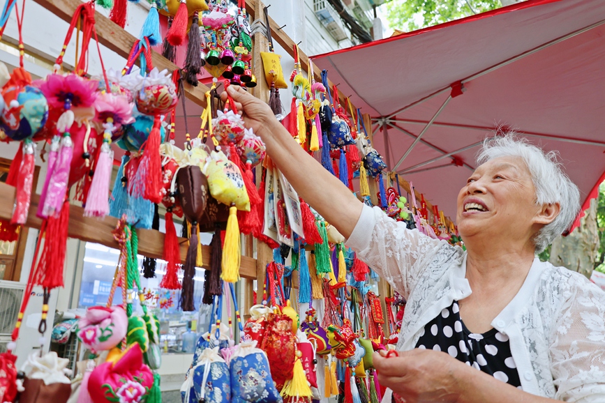6月19日，在河南省第十四屆中華軒轅龍舟大賽（淅川站）現場的龍舟集市，老手藝人陳秀閣展示自己制作的香囊。盧晉滎攝
