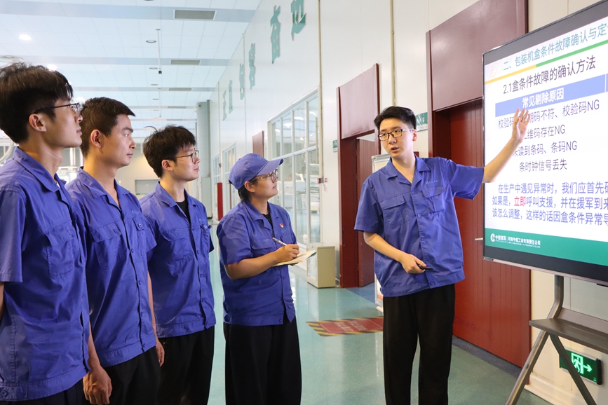 图为信息点检工为青工讲授设备操作技巧。贺艳奇摄