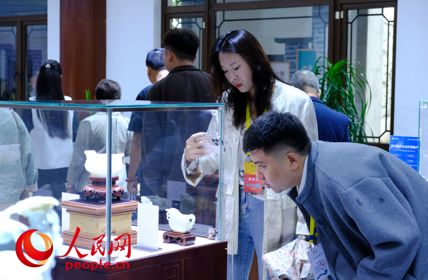 参观者探身端详玻璃柜内的玉雕作品。人民网记者 常力元摄
