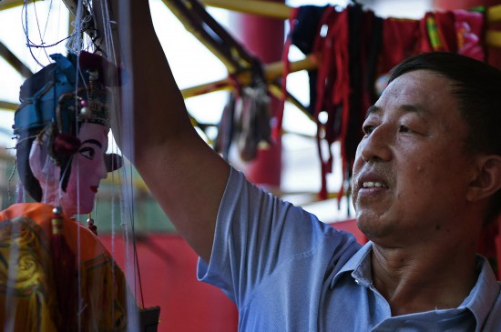 在江西省广昌县塘坊镇大株村，木偶剧团团长谢帮银在组装一个提线木偶（8月10日摄）。