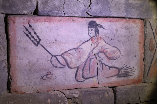 在嘉峪关魏晋墓六号墓的画像砖上，一侍女手持三股叉串好的烤肉（5月13日摄）。新华社记者 马希平 摄