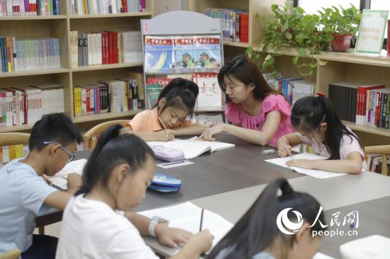 大学路街道嵩山社区的暑托班上，小朋友们在老师的辅导下做暑假作业。人民网记者 慎志远摄