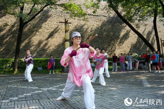 市民在西安城墙下的环城公园内练习龙形鞭杆。李欣宇 摄