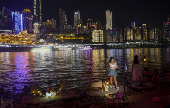 8月23日，重庆江北区嘉陵江畔，游客们在迷人的重庆夜景中打卡拍照。新华社记者 刘潺 摄