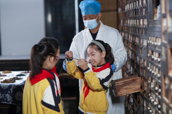 10月22日，在江苏省兴化市一家中药店，兴化市实验小学学生在中药师的指导下体验抓中草药。新华社发（周社根摄）